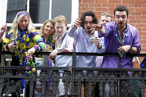 FILE - In this Tuesday, Feb. 25, 2020, file photo, a group of revelers on a balcony toss beads to the crowd below on Bourbon Street on Mardi Gras day in New Orleans. A month ago, the streets were awash in people and the city was steeped in its most cherished tradition of communal joy: Carnival season was nearing its Mardi Gras climax, with parades rolling, beer flowing and money changing hands at bars and restaurants.
But now since the coronavirus outbreak, the bars are closed and restaurants struggle with take-out- or delivery-only operations &#151; the ones that stay open. (AP Photo/Rusty Costanza, File)