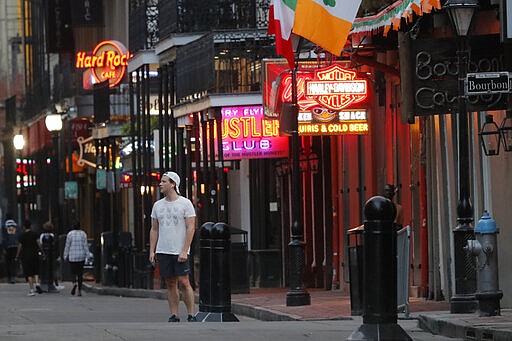 FILE - In this Thursday, March 19, 2020, file photo, a man stands and looks around on a nearly empty Bourbon Street, usually bustling with tourism and revelers in New Orleans. A month ago, the streets were awash in people and the city was steeped in its most cherished tradition of communal joy: Carnival season was nearing its Mardi Gras climax, with parades rolling, beer flowing and money changing hands at bars and restaurants. Since the coronavirus outbreak, the bars are closed and restaurants struggle with take-out- or delivery-only operations &#151; the ones that stay open. (AP Photo/Gerald Herbert, File)