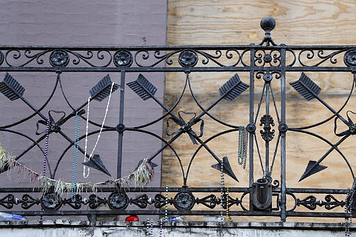 FILE - In this Thursday, March 19, 2020, file photo, remnants of the Mardi Gras celebration are seen on a balcony in front of boarded windows of a now shuttered bar, on Bourbon Street, which is normally bustling with tourism and revelers, in the French Quarter of New Orleans. Since the coronavirus outbreak, the bars are now closed and restaurants struggle with take-out- or delivery-only operations &#151; the ones that stay open. (AP Photo/Gerald Herbert, File)