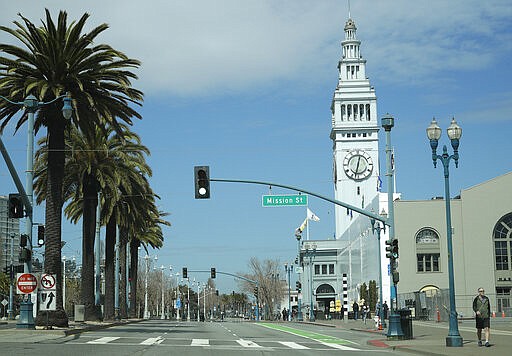 People walk along the Embarcadero on Sunday, March 22, 2020, in San Francisco. Some 40 million Californians are coping with their first weekend under a statewide order requiring them to stay at home to help curb the spread of the coronavirus. (AP Photo/Ben Margot)