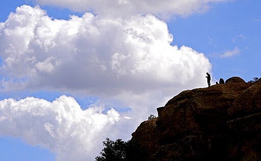 A hiker stands atop a rock formation at Stoney Point Park, Sunday, March 22, 2020, in the Chatsworth section of Los Angeles. California Gov. Gavin Newsom ordered the state's 40 million residents to stay at home indefinitely. His order restricts non-essential movements to control the spread of the coronavirus that threatens to overwhelm the state's medical system. (AP Photo/Mark J. Terrill)