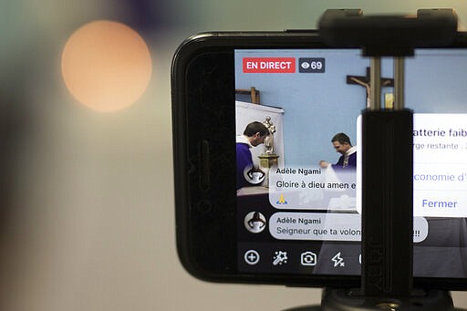 A livestream viewer comments &quot;glory be to god, amen&quot; during a closed door Sunday mass livestream at the St. Vincent de Paul church in Marseille, southern France, Sunday, March 22, 2020. As mass gatherings are forbidden due to measures to prevent the spread of COVID- 19, priests are using technology to reach worshippers forced to stay at home. For most people, the new coronavirus causes only mild or moderate symptoms. (AP Photo/Daniel Cole)