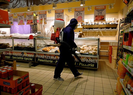 A man sanitizes a supermarket after closure, in Rome, Sunday, March 22, 2020. For most people, the new coronavirus causes only mild or moderate symptoms. For some it can cause more severe illness, especially in older adults and people with existing health problems. (Mauro Scrobogna/LaPresse via AP)