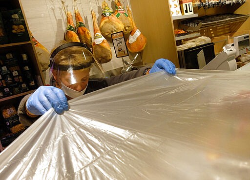 An employee of a supermarket protects food before proceeding with sanitization operations at closure, in Rome, Sunday, March 22, 2020. For most people, the new coronavirus causes only mild or moderate symptoms. For some it can cause more severe illness, especially in older adults and people with existing health problems. (Mauro Scrobogna/LaPresse via AP)