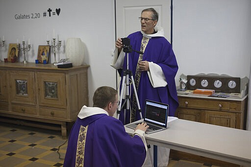 Priest Philippe Rochas, left, and Jean-Benoit de Beauchene pack up livestreaming equipment after holding a closed door Sunday mass at the St. Vincent de Paul church in Marseille, southern France, Sunday, March 22, 2020. As mass gatherings are forbidden due to measures to prevent the spread of COVID- 19, priests are using technology to reach worshippers forced to stay at home. For most people, the new coronavirus causes only mild or moderate symptoms. (AP Photo/Daniel Cole)