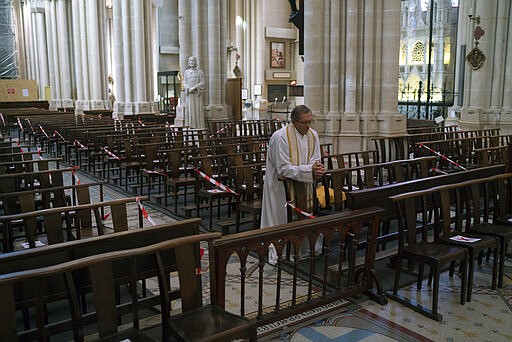 Priest Jean-Benoit de Beauchene prays in the empty St. Vincent de Paul church in Marseille, southern France, Sunday, March 22, 2020. As mass gatherings are forbidden due to measures to prevent the spread of COVID- 19, priests are using technology to reach worshippers forced to stay at home. For most people, the new coronavirus causes only mild or moderate symptoms. (AP Photo/Daniel Cole)