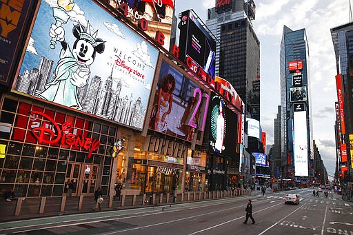 A police officer walks across an empty 7th Avenue in a sparsely populated Times Square due to COVID-19 concerns, Friday, March 20, 2020, in New York. New York Gov. Andrew Cuomo is ordering all workers in non-essential businesses to stay home and banning gatherings statewide. Nonessential gatherings of individuals of any size or for any reason are canceled or postponed. (AP Photo/John Minchillo)