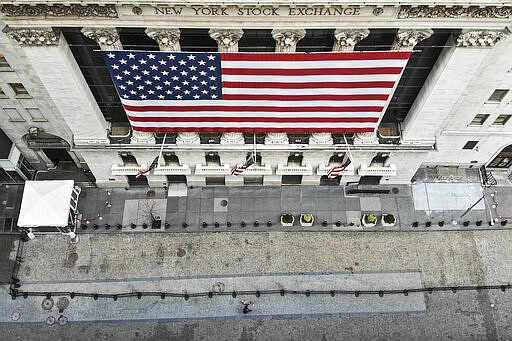 In this March 21, 2020 photo, a lone pedestrian walks his dog past the New York Stock Exchange as COVID-19 concerns empty a typically bustling downtown area in New York. New York Gov. Andrew Cuomo announced sweeping orders Friday that will severely restrict gatherings of any size for the state's more than 19 million residents and will require workers in nonessential businesses to stay home. (AP Photo/John Minchillo)