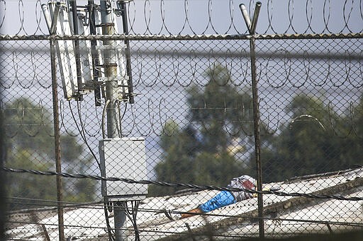 The body of a man lies on a roof of La Modelo jail in Bogota, Colombia, Sunday, March 22, 2020. Violence broke out in the prison out of inmates' fears that authorities are not doing enough to prevent coronavirus inside overcrowded prisons. (AP Photo/Ivan Valencia)