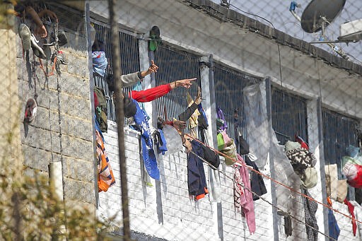 Inmates point from inside of La Modelo jail in Bogota, Colombia, Sunday, March 22, 2020. Violence broke out in the prison out of inmates' fears that prison guards are not doing enough to prevent coronavirus inside overcrowded prisons. (AP Photo/Ivan Valencia)