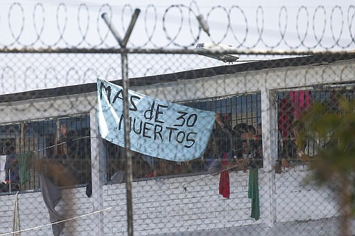 Inmates display a sign reading in Spanish &quot;More than 30 dead&quot; at La Modelo jail in Bogota, Colombia, Sunday, March 22, 2020. Violence broke out in the prison out of inmates' fears that authorities are not doing enough to prevent coronavirus inside overcrowded prisons. (AP Photo/Ivan Valencia)