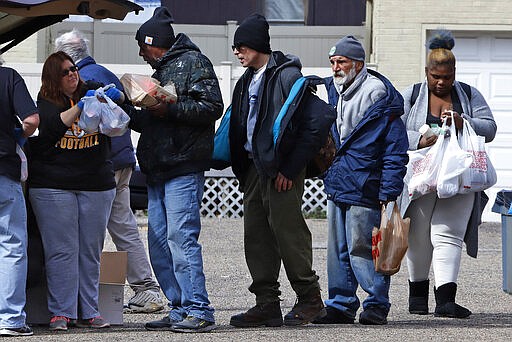 Meals usually served for the homeless and underemployed from the kitchen in the fellowship hall of the former New Hope Methodist Church on Pittsburgh's Northside, are handed out from the back of a van in the church's parking lot to mitigate the community spread of COVID-19, Sunday, March 22, 2020. The meals have been served for over 25 years as part of the United Methodist Church Union's Daily Bread feeding program. (AP Photo/Gene J. Puskar)