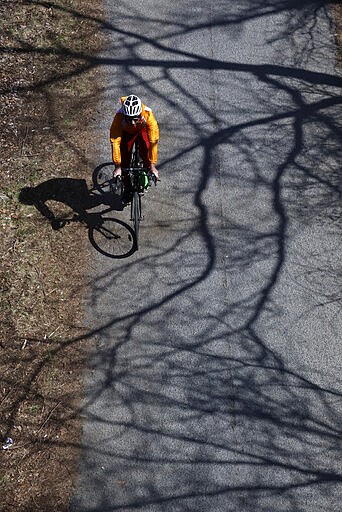 A bicyclist rides on the Allegheny Heritage on a sunny afternoon on the Northside of Pittsburgh, Sunday, March 22, 2020. (AP Photo/Gene J. Puskar)