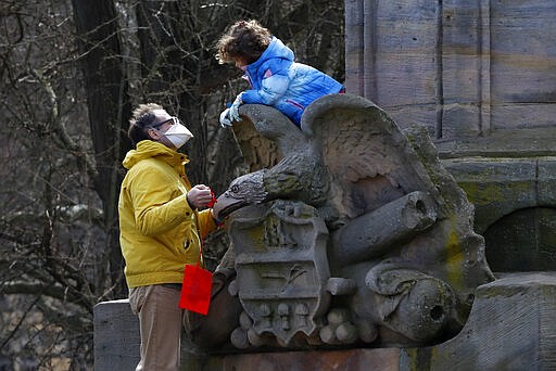 A man and a little girl play on a memorial to Civil War veterans in West Park on the Northside of Pittsburgh on a sunny Sunday, March 22, 2020. (AP Photo/Gene J. Puskar)