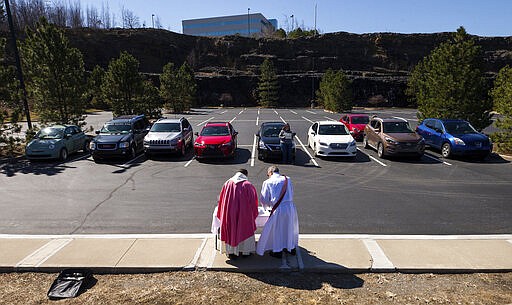 Rev. William A. Mentz, pastor of the Scranton, Pa. based St. Francis and Clare Progressive Catholic Church, and church deacon Frank Gillette celebrate a Catholic mass for the faithful sitting in their cars in a parking lot at the Shoppes at Montage in Moosic, Pa. on Sunday, March 22, 2020. The Progressive Catholic Church is a small denomination operating independently of the Roman Catholic Church. Other Catholic churches in the Scranton area suspended the celebration of mass to help control the spread of COVID-19. (Christopher Dolan/The Times-Tribune via AP)