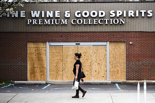 A pedestrian walks past a boarded up Wine and Spirits store in Philadelphia, Friday, March 20, 2020. Pennsylvania Gov. Tom Wolf directed all &quot;non-life-sustaining&quot; businesses to close their physical locations late Thursday and said state government would begin to enforce the edict starting early Saturday. (AP Photo/Matt Rourke)