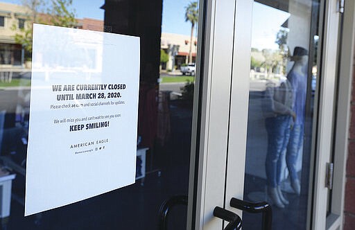 A sign on the door to American Eagle in The Village inside the Yuma Palms Regional Center states the store is closed until March 28, due to coronavirus and to &quot;Keep Smiling!&quot;. (Randy Hoeft/The Yuma Sun via AP)