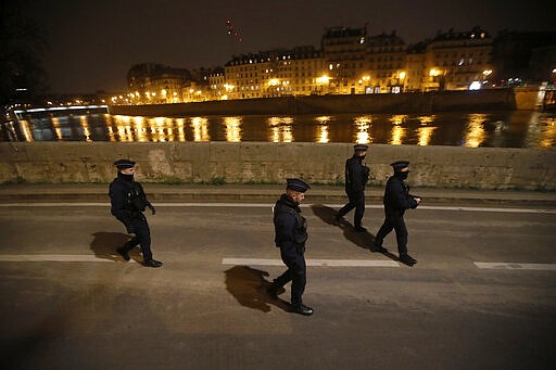 French policemen walk along the Seine river during a control in Paris, Friday, March 20, 2020. French President Emmanuel Macron said that for 15 days people will be allowed to leave the place they live only for necessary activities such as shopping for food, going to work or taking a walk. For most people, the new coronavirus causes only mild or moderate symptoms. For some it can cause more severe illness, especially in older adults and people with existing health problems. (AP Photo/Christophe Ena)