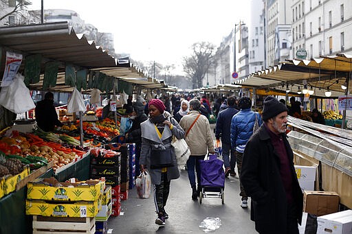 People walk in the open air market of Belleville, in Paris, Friday, March 20, 2020. French President Emmanuel Macron said that for 15 days starting at noon on Tuesday, people will be allowed to leave the place they live only for necessary activities such as shopping for food, going to work or taking a walk. For most people, the new coronavirus causes only mild or moderate symptoms. For some it can cause more severe illness, especially in older adults and people with existing health problems. (AP Photo/Thibault Camus)