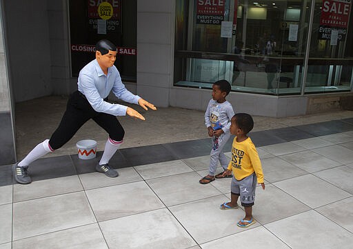 A mime artist performs for two children after getting a donation at a virtually empty Mall in Johannesburg, Sunday, March 22, 2020. There is a noticeable drop in crowds of shoppers at malls due the spread of the coronavirus. For most people the virus causes only mild or moderate symptoms . For others it can cause more severe illness, especially in older adults and people with existing health problems. (AP Photo/Denis Farrell)