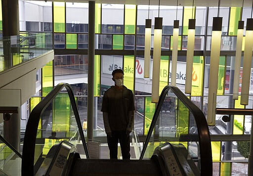 A masked shopper leaves a virtually empty shopping mall in Johannesburg, Sunday, March 22, 2020. There is a noticeable drop in crowds of shoppers at malls due the spread of the coronavirus. For most people the virus causes only mild or moderate symptoms . For others it can cause more severe illness, especially in older adults and people with existing health problems. (AP Photo/Denis Farrell)