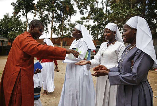 Christian faithful of the Legio Maria African Mission sanitize their hands before attending a Sunday mass service in the Kibera slum of the capital Nairobi, Kenya Sunday, March 22, 2020. In Kenya, the Ministry of Health has banned all public gatherings and meetings in order to limit the spread of the new coronavirus that causes COVID-19 but has permitted normal church services to continue so long as they provide hand sanitizing or washing facilities to attendees. (AP Photo/Brian Inganga)