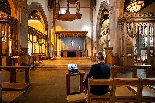 A church parishioner watches a laptop inside Liverpool Parish Church (Our Lady and St Nicholas) in Liverpool, England, during the Church of England's first virtual Sunday service given by the Archbishop of Canterbury Justin Welby, after the archbishops of Canterbury and York wrote to clergy on Tuesday advising them to put public services on hold in response to Government advice to avoid mass gatherings to help prevent the spread of the Covid-19 virus. For most people, the new coronavirus causes only mild or moderate symptoms. For some it can cause more severe illness. (Peter Byrne/PA via AP)