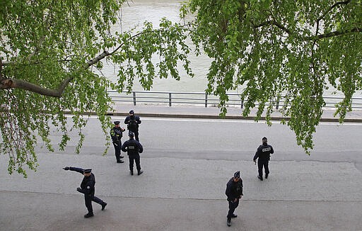 Police officers patrol along the Seine rive bank in Paris, Friday, March 20, 2020. Paris police imposed a ban for the next days on the Seine River banks to fight the spread of the coronavirus. For most people, the new coronavirus causes only mild or moderate symptoms, such as fever and cough. For some, especially older adults and people with existing health problems, it can cause more severe illness, including pneumonia. (AP Photo/Michel Euler)