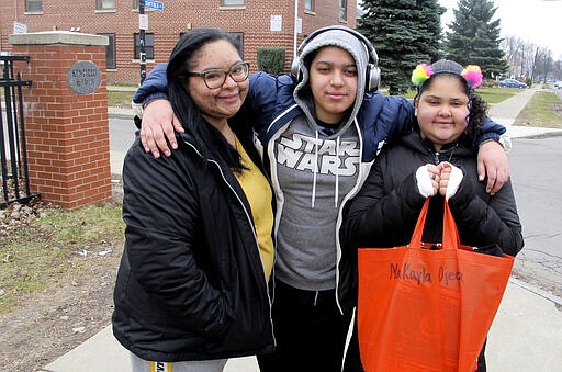 BIn this March 17, 2020 photo, Roxanne Ojeda-Valentin left poses with her and children, Malachi and Makayla Ojeda, after leaving Frederick Law Olmsted school in Buffalo, N.Y., where they picked up text books and assignments to work on while the district is closed by the coronavirus. Parents everywhere are being thrust into the role of primary educators of their children amid the outbreak. (AP Photo/Carolyn Thompson)