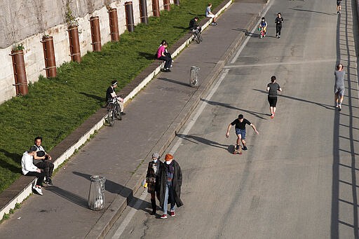 Parisians enjoy the sun along the Seine Bank, in Paris, Wednesday, March 18, 2020. French President Emmanuel Macron said that for 15 days people will be allowed to leave the place they live only for necessary activities such as shopping for food, going to work or taking a walk. For most people, the new coronavirus causes only mild or moderate symptoms. For some it can cause more severe illness, especially in older adults and people with existing health problems. (AP Photo/Francois Mori)