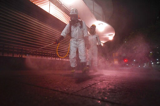 City workers spray disinfectant as a preventive measure against the spread of the new coronavirus in Caracas, Venezuela, Sunday, March 22, 2020. (AP Photo/Matias Delacroix)