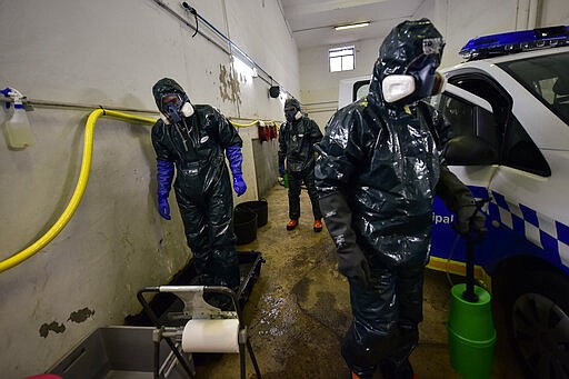 Volunteers workers of Search and Rescue (SAR) with special equipment, disinfect a police car at Local Police station to prevent the spread of coronavirus COVID-19, in Pamplona, northern Spain, Sunday, March 22, 2020. For some people the COVID-19 coronavirus causes mild or moderate symptoms, but for some it causes severe illness. (AP Photo/Alvaro Barrientos)