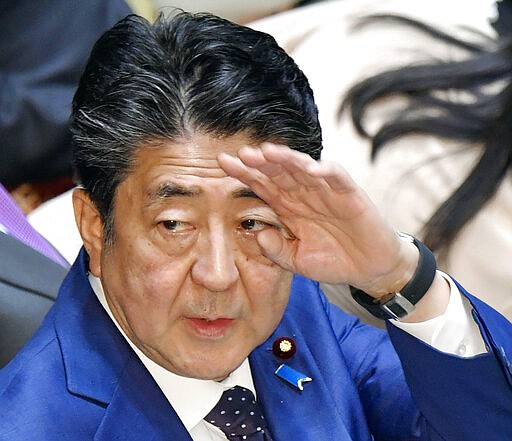 Japan&#146;s Prime Minister Shinzo Abe raises his hand during a parliamentary session in Tokyo Monday, March 23, 2020. Abe said a postponement of Tokyo Olympics would be unavoidable if the games cannot be held in a complete way because of the coronavirus pandemic. (Yoshitaka Sugawara/Kyodo News via AP)