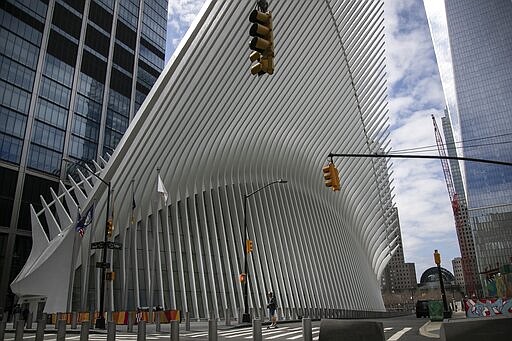 A man is dwarfed against the transportation hub and shopping mall known as the Oculus as he rides his skateboard in downtown Manhattan on Sunday, March 22, 2020, in downtown New York. New York City's mayor prepared Sunday to order his city behind closed doors in an attempt to slow a pandemic that has swept across the globe and threatened to make the city of 8.5 million one of the world's biggest coronavirus hot spots. (AP Photo/Wong Maye-E)