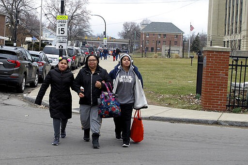 In this March 17, 2020 photo, Makayla Ojeda, left, walks with her mother, Roxanne Ojeda-Valentin and brother, Malachi Ojeda after leaving Frederick Law Olmsted school in Buffalo, N.Y., where they picked up text books and assignments to work on while the district is closed by the coronavirus. Parents everywhere are being thrust into the role of primary educators of their children amid the outbreak. (AP Photo/Carolyn Thompson)