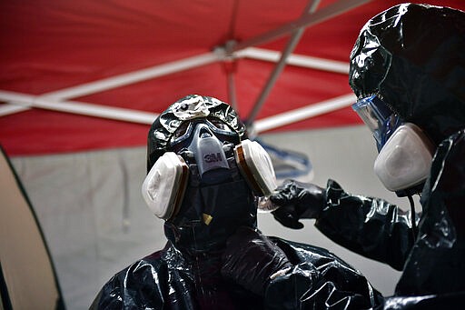 Volunteers workers of Search and Rescue (SAR) with special equipment, in a special place to disinfect theirself, after disinfecting police car at Local Police station to prevent the spread of coronavirus COVID-19, in Pamplona, northern Spain, Sunday, March 22, 2020. For some people the COVID-19 coronavirus causes mild or moderate symptoms, but for some it causes severe illness. (AP Photo/Alvaro Barrientos)