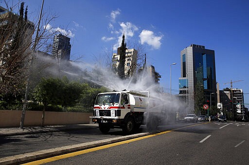 A municipal tanker sprays disinfectant as a precaution against the coronavirus outbreak in Beirut, Lebanon, Sunday, March 22, 2020. Lebanon has been taking strict measures to limit the spread of the coronavirus closing restaurants and nightclubs as well as schools and universities. For most people, the new coronavirus causes only mild or moderate symptoms. For some it can cause more severe illness. (AP Photo/Bilal Hussein)