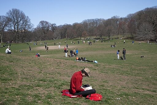 A man reads his book in Prospect Park in the Brooklyn borough of New York on Sunday, March 15, 2020. President Donald Trump on Sunday called on Americans to cease hoarding groceries and other supplies, while one of the nation's most senior public health officials called on the nation to act with more urgency to safeguard their health as the coronavirus outbreak continued to spread across the United States. (AP Photo/Wong Maye-E)