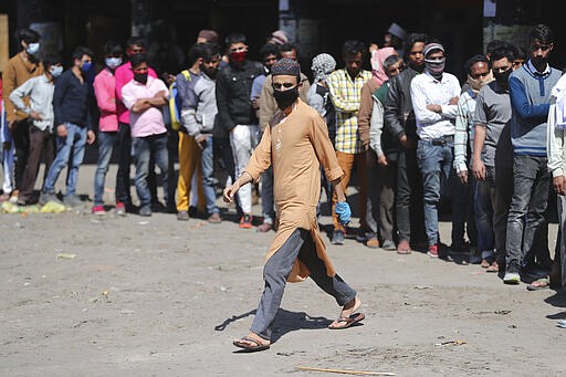 Indian passengers who got stranded at a bus terminal line up for free food being distributed by shop keepers during a day long lockdown amid growing concerns of coronavirus in Jammu, India, Sunday, March 22, 2020. India is observing a 14-hour &#147;people's curfew&#148; called by Prime Minister Narendra Modi in order to stem the rising coronavirus caseload in the country of 1.3 billion. For most people, the new coronavirus causes only mild or moderate symptoms. For some it can cause more severe illness. (AP Photo/Channi Anand)