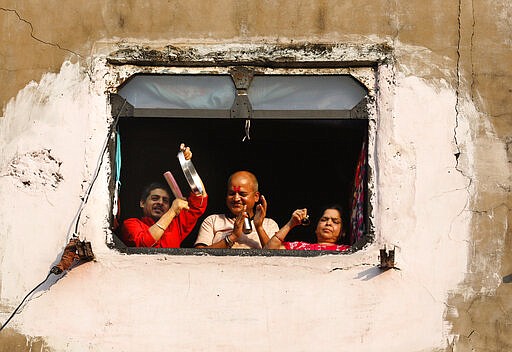 A family bang pans and claps from the window of their house in show of appreciation to health care workers in Prayagraj, India, Sunday, March 22, 2020. India is observing a 14-hour &quot;people's curfew&quot; called by Prime Minister Narendra Modi in order to stem the rising coronavirus caseload in the country of 1.3 billion. For most people, the new coronavirus causes only mild or moderate symptoms. For some it can cause more severe illness (AP Photo/Rajesh Kumar Singh)