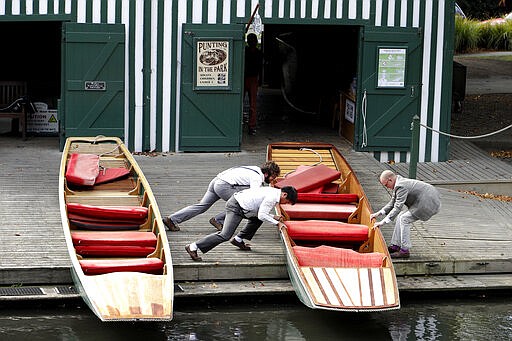 Staff put their boats away on the banks of the Avon River in central Christchurch, New Zealand, Monday, March 23, 2020. New Zealand Prime Minister Jacinda Ardern announced Monday that schools and non-essential services across New Zealand will be closed as part of the measures as the government put the country in lockdown to try to stop the spread of coronavirus pandemic. (AP Photo/Mark Baker)