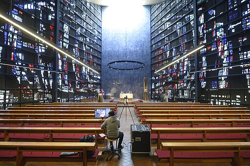 Parish vicar Patrick Stauss conducts a service of the catholic parish of the Assumption of Mary via YouYube in an empty church in Winterbach, Germany, Sunday, March 22, 2020. For most people, the new coronavirus causes only mild or moderate symptoms, such as fever and cough. For some, especially older adults and people with existing health problems, it can cause more severe illness, including pneumonia. (Sebastian Gollnow/dpa via AP)