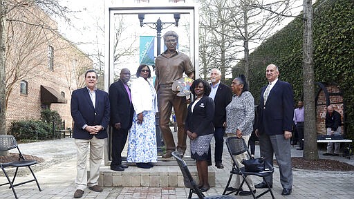 In this Wednesday, March 18, 2020 photo, Florence, S.C., City Councilman Glynn F. Willis, William Cooper, Isla Willette Myers, Councilwoman Teresa Myers Ervin, Alex Palkovich, and City Council members Pat Gibson-Hye Moore and George D. Jebaily pose for a photo after the city of Florence unveiled a statue of William H. Johnson in the West Evans Street Breezeway. (Matthew Christian/The Morning News via AP)