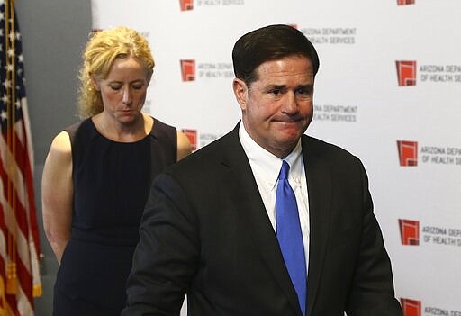 Arizona Gov. Doug Ducey, right, and Arizona Department of Health Services Director Dr. Cara Christ, left, exit a news conference after providing an update on the coronavirus at the Arizona State Public Health Laboratory Monday, March 23, 2020, in Phoenix. (AP Photo/Ross D. Franklin)