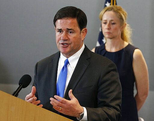 Arizona Gov. Doug Ducey, left, answers a question as he is joined by Arizona Department of Health Services Director Dr. Cara Christ, right, as they provide an update on the coronavirus during a news conference at the Arizona State Public Health Laboratory Monday, March 23, 2020, in Phoenix. (AP Photo/Ross D. Franklin)