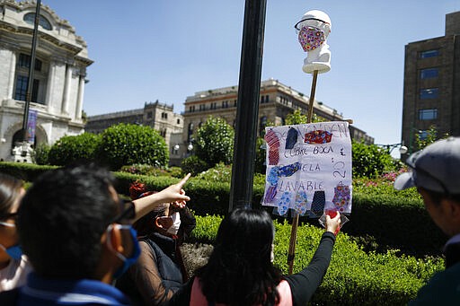 Customers pick out homemade fabric face masks being sold for 20 pesos (around 85 cents) from Jorge Rodriquez, 48, on the street in central Mexico City, Monday, March 23, 2020. Rodriguez was recently laid off from his construction job until further notice, and so he and his wife began making and selling the masks. &quot;You have a family. You have to bring home money,&quot; said Rodriguez. &quot;I'm a little afraid, but you have to find a solution for the household costs.&quot; Beginning Monday, Mexico's capital shut down museums, bars, gyms, churches, and other non-essential businesses that gather large numbers of people, in an attempt to slow the spread of the new coronavirus.(AP Photo/Rebecca Blackwell)