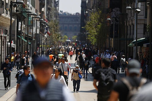 Pedestrians walk along Madero Street in Mexico City, Monday, March 23, 2020. Beginning Monday, Mexico's capital shut down museums, bars, gyms, churches, and other non-essential businesses that gather large numbers of people, in an attempt to slow the spread of the new coronavirus. (AP Photo/Rebecca Blackwell)