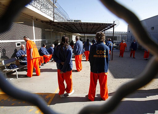 FILE - In this Jan. 12, 2012, file photo, inmates walk around a recreation yard at the Deuel Vocational Institution in Tracy, Calif. One inmate and five employees in California&#146;s massive prison system have tested positive for coronavirus, leading to increased pressure Monday, March 23, 2020, on corrections officials to begin releasing some of the state&#146;s 123,000 convicts early. (AP Photo/Rich Pedroncelli, File)