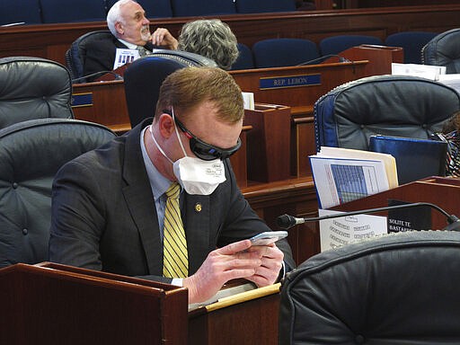 Alaska state Rep. David Eastman sits at his desk on the House floor in Juneau, Alaska, Monday, March 23, 2020. Eastman, a Wasilla Republican, has been critical of the Legislature's planning around the coronavirus. Rep. Sharon Jackson also wore a mask on the House floor Monday. (AP Photo/Becky Bohrer)