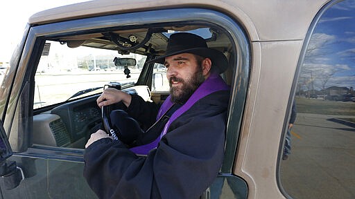 Father Stephen Tilley sits behind his steering wheel during the &quot;Meet Me at the Jeep,&quot; for a drive-up confession at Skaggs Catholic Center, Sunday, March 22, 2020, in Draper, Utah. With the threat of the new coronavirus closing churches, some Catholic priests in Utah offered to hear drive-up confessions. (AP Photo/Rick Bowmer)